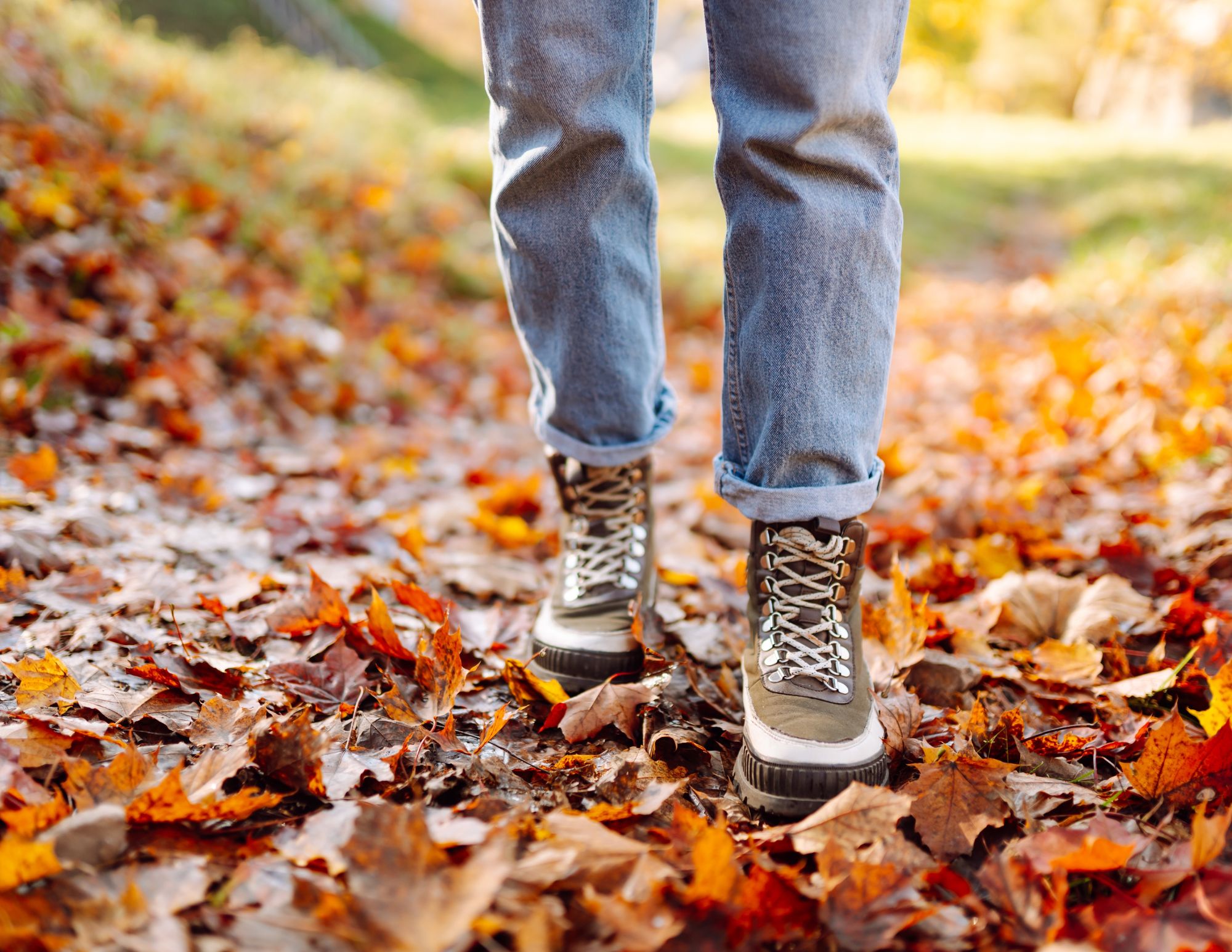 a person walking on a trail with fall leaves
